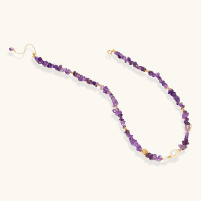 Beaded necklace with purple amethyst chips, freshwater pearls, and gold accents on white background.