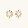 Circular gold stud earrings with iridescent mother-of-pearl center and green zirconia accents on cream background.