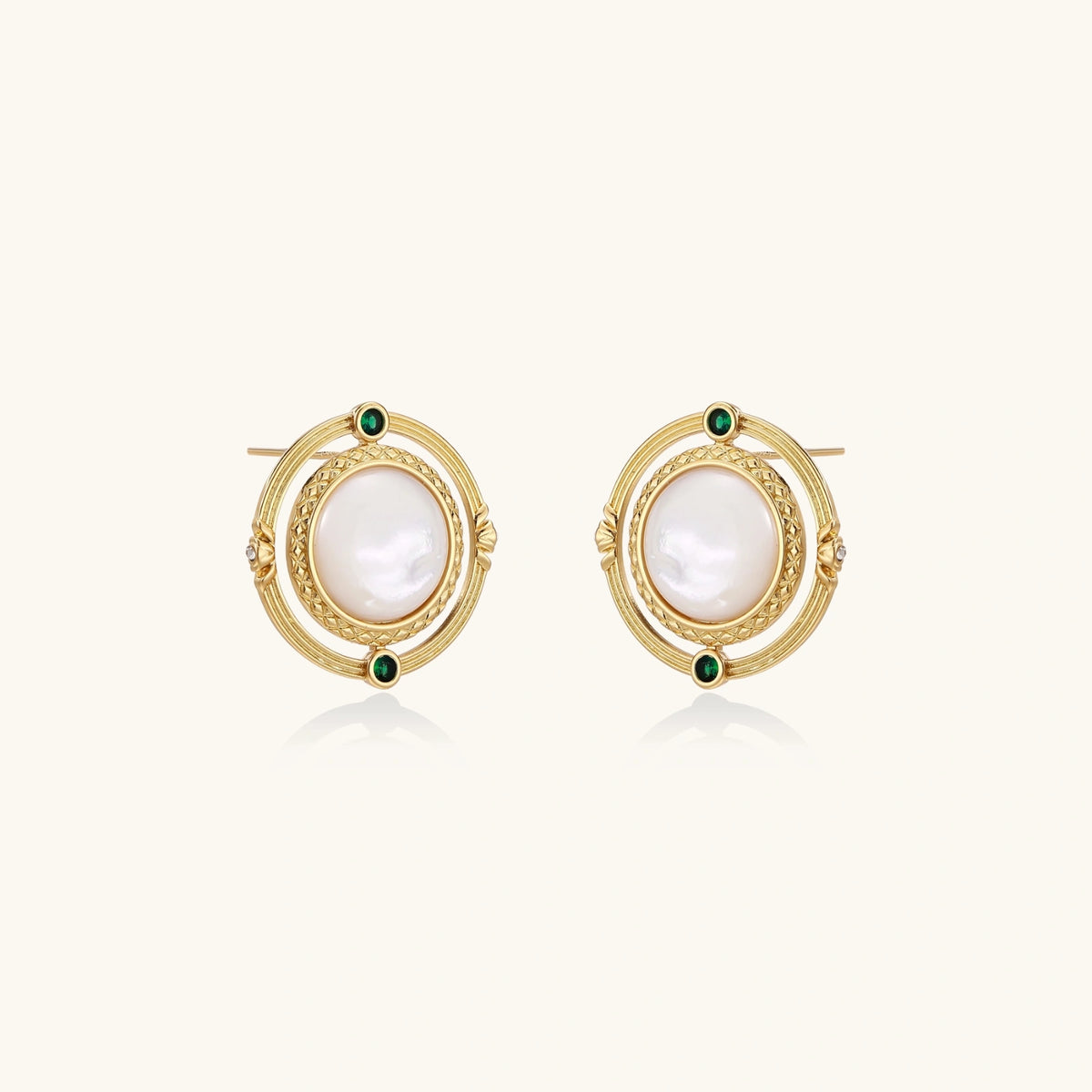 Circular gold stud earrings with iridescent mother-of-pearl center and green zirconia accents on cream background.