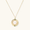 Gold pendant necklace with circular orbital design, iridescent mother-of-pearl center, and green zirconia accents