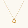 Delicate gold-plated necklace with three interlocking circle rings forming a minimalist knot pendant on cream background