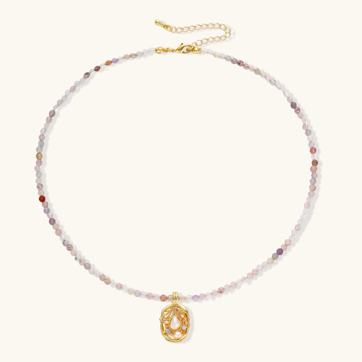 Delicate gold-plated necklace with mixed gemstone beads and ornate oval pendant on white background
