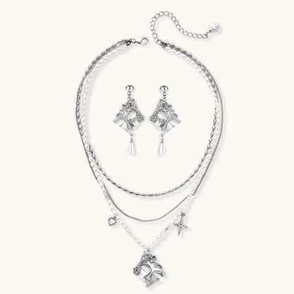 Ornate silver-toned masquerade mask jewelry set featuring rhinestone details and pearl drop earrings on white background.