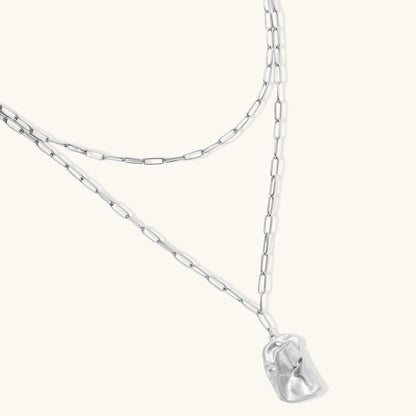 Modern textured hoop earrings and layered chain necklace with liquid metal pendant in silver and gold finishes.