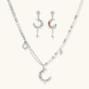 Mixed-metal jewelry set featuring layered necklaces with crescent moon pendant and pearl beads, plus matching star-drop earrings.