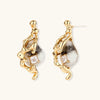 Close-up of metallic dragon-wrapped earrings with marbled resin stones on white background