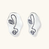 Artistic ear-shaped earrings with minimalist face line art on clear eco-zinc alloy base with sterling silver posts.