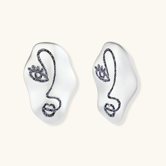 Artistic ear-shaped earrings with minimalist face line art on clear eco-zinc alloy base with sterling silver posts.