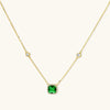Delicate gold chain necklace featuring square emerald pendant with crystal halo and station accents