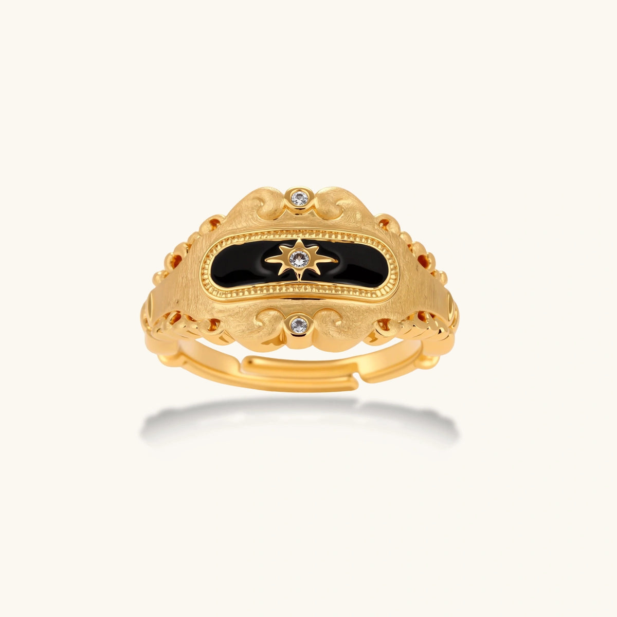 Ornate 18K gold-plated ring with black enamel center featuring star motif and decorative baroque-style edges on white background.
