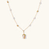Delicate 18k gold-plated chain with baroque pearls and colorful enamel pendant featuring blue, pink accents on cream background.
