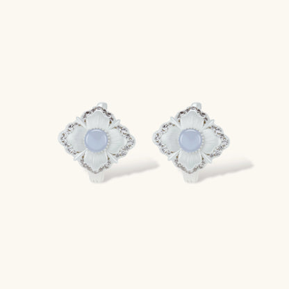 Silver-plated flower earrings with blue zirconia centers, featuring one stud and one huggie hoop in mismatched pair style.