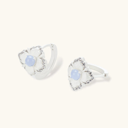Silver-plated flower earrings with blue zirconia centers, featuring one stud and one huggie hoop in mismatched pair style.