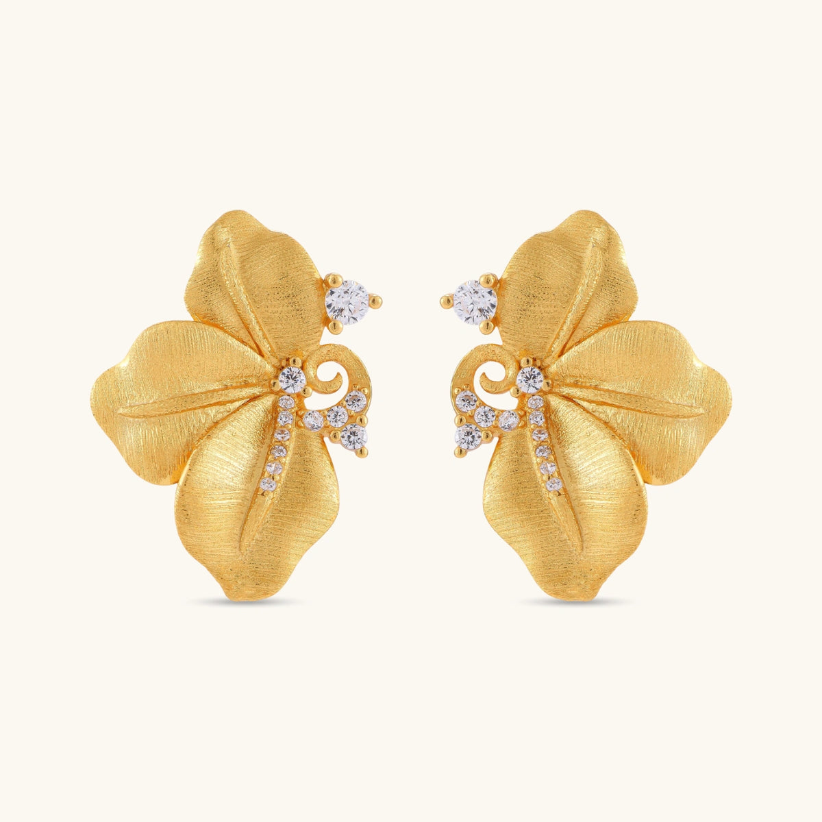 Gold-plated 925 silver flower stud earrings with brushed finish, swirl detail, and pavé cubic zirconia on cream background.
