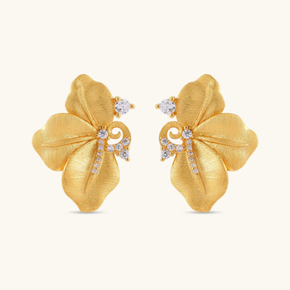 Gold-plated 925 silver flower stud earrings with brushed finish, swirl detail, and pavé cubic zirconia on cream background.