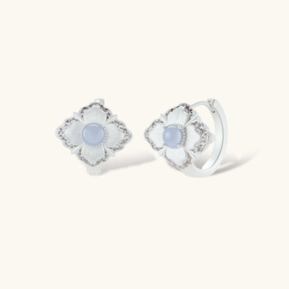Silver-plated flower earrings with blue zirconia centers, featuring one stud and one huggie hoop in mismatched pair style.
